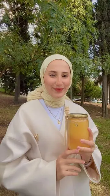 Melike parkta, elinde ağzına kadar dolu bir bal kavanozu tutuyor